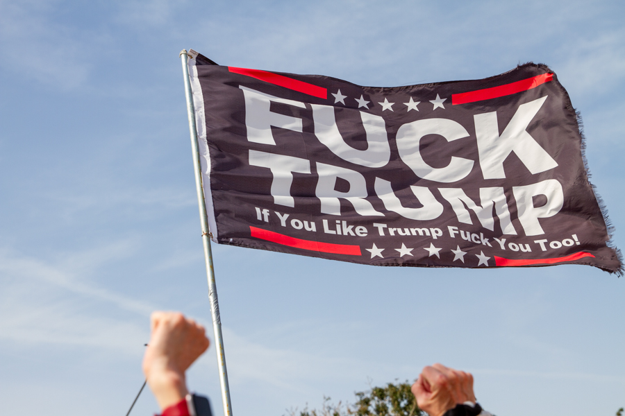 Close up of black Fuck Trump flag waving in wind with raised fists at Goodyear AZ rally