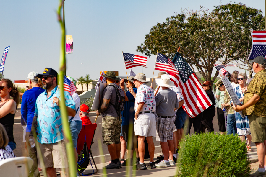 Protesters waving American flags along a street sidewalk at a Goodyear Arizona rally
