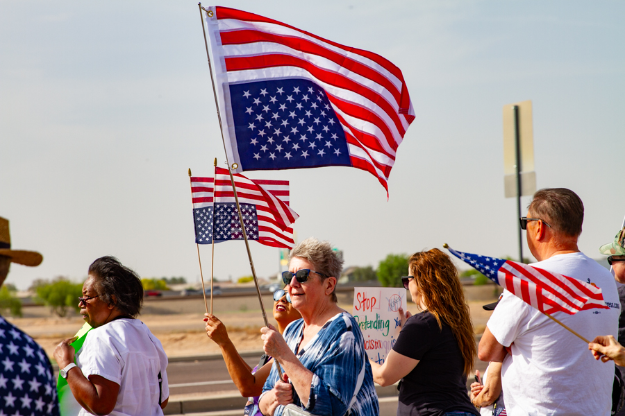 Protesters holding an upside down American flag and small hand flags at a Goodyear Arizona demonstration