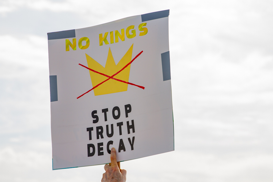 A sign held up reading No Kings Stop Truth Decay with a crossed out crown at a Goodyear Arizona rally