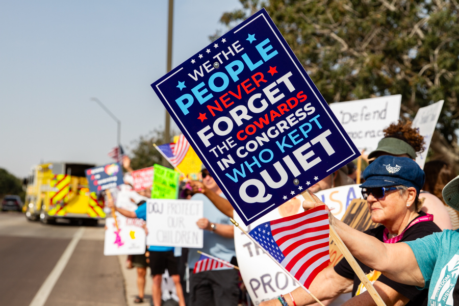 Protesters holding a large sign reading We The People Never Forget The Cowards In Congress Who Kept Quiet at a Goodyear Arizona rally