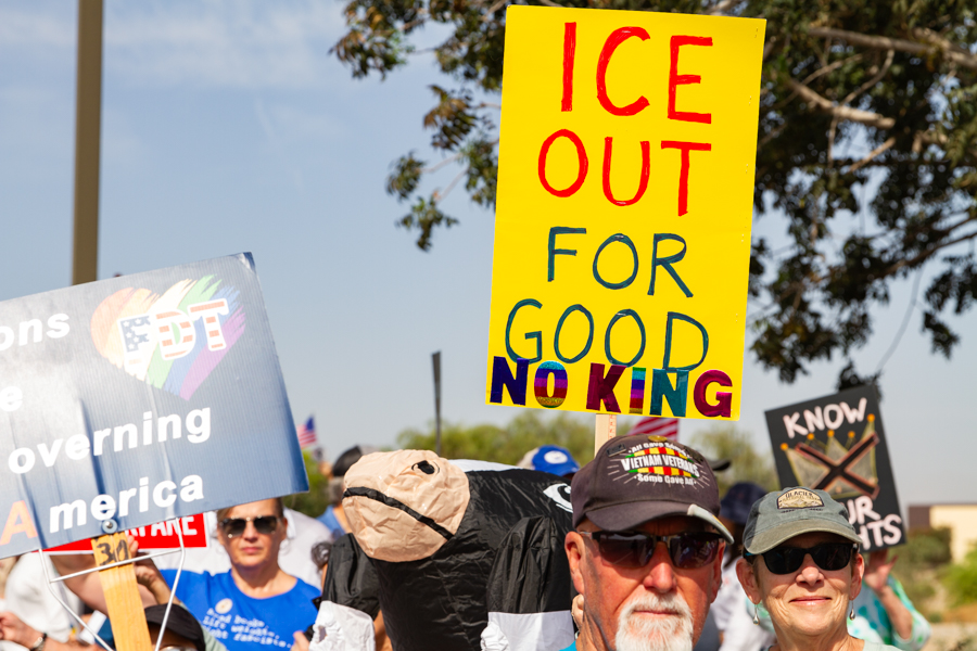 Protesters with a bright yellow sign reading ICE Out For Good No King at a Goodyear Arizona demonstration