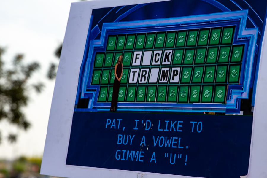 A sign styled like Wheel of Fortune reading Pat I'd like to buy a vowel Gimme a U to solve Fuck Trump at a Goodyear Arizona rally