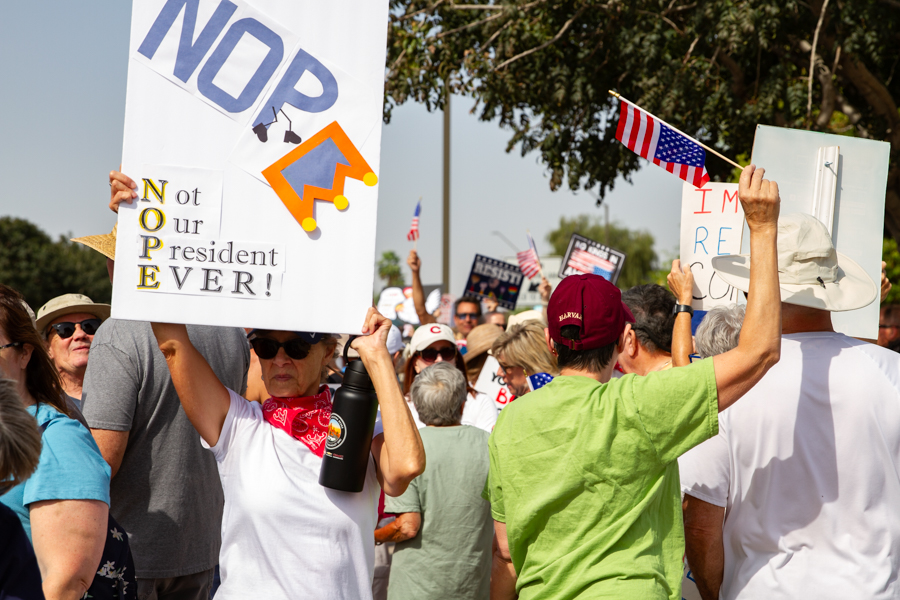 Protest crowd line holding a sign reading NOPE Not Our President EVER with a crown graphic at a Goodyear Arizona rally