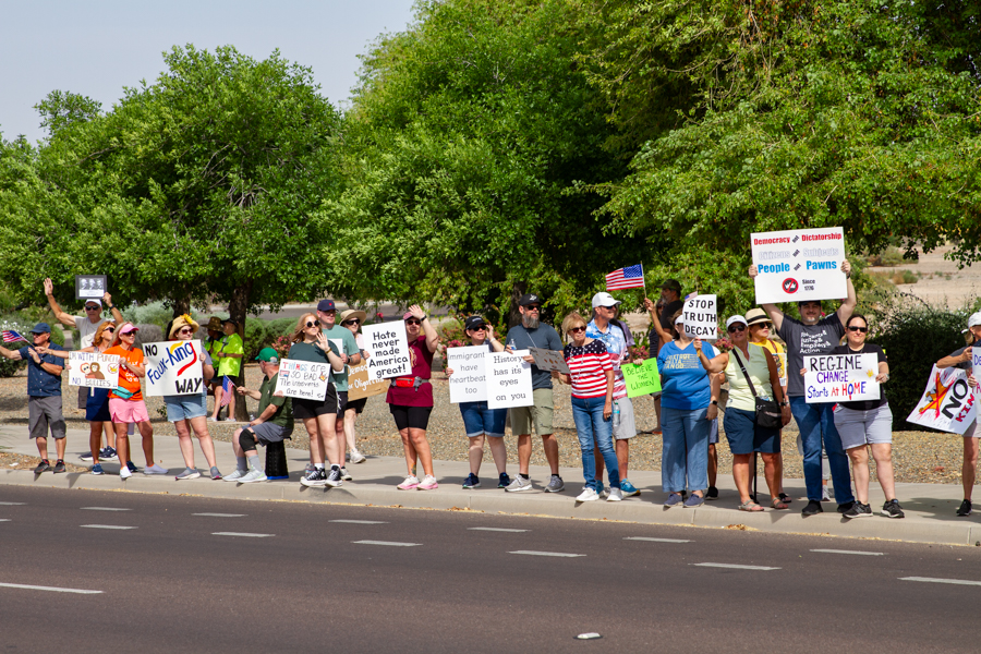 Protesters holding No Faux-King Way and Hate Never Made America Great signs at a Goodyear Arizona demonstration