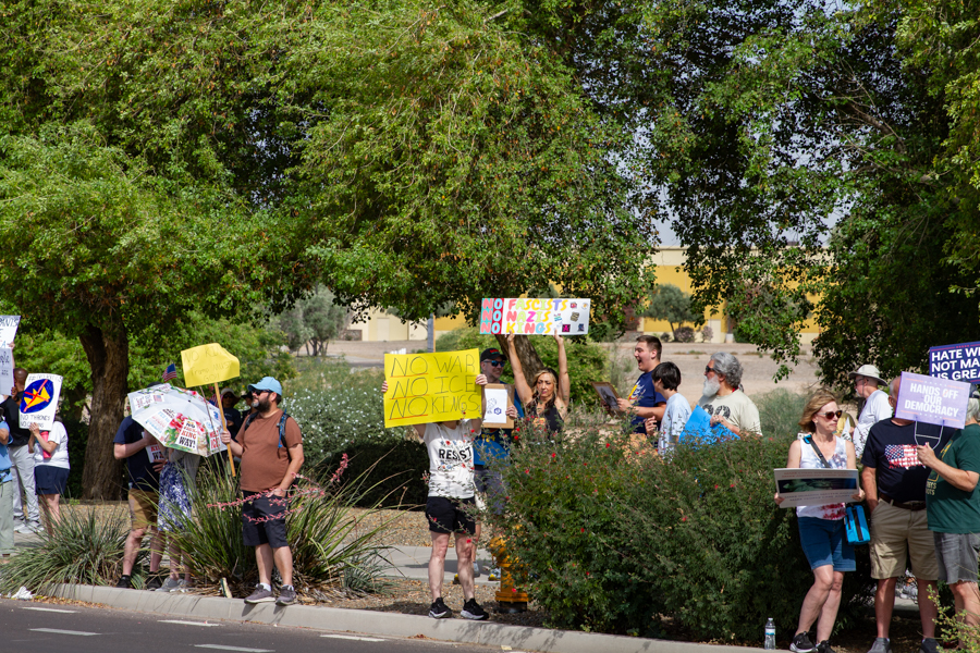 Protesters with a customized No Faux-King Way umbrella and colorful No Fascists No Nazis No Kings sign at a Goodyear Arizona rally