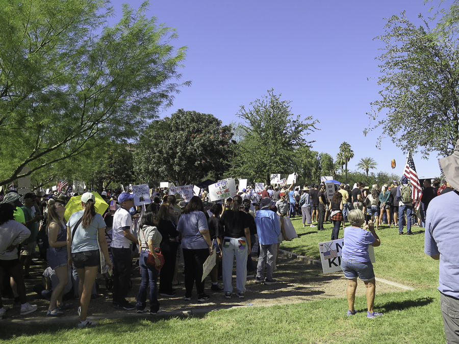 Wide crowd shot of demonstrators holding signs and American flags at the No Kings 2.0 protest rally in Phoenix