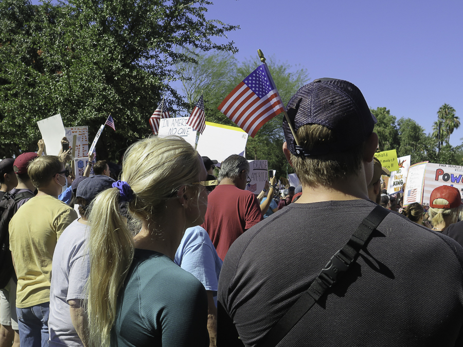 Activists holding American flags and patriotic signs inside the crowd at the No Kings 2.0 rally in Phoenix