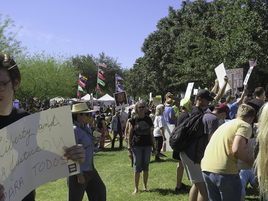 Phoenix No Kings 2.0 rally crowd featuring a bilingual Liberty and Justice Para Todos sign and a Donald Trump portrait poster