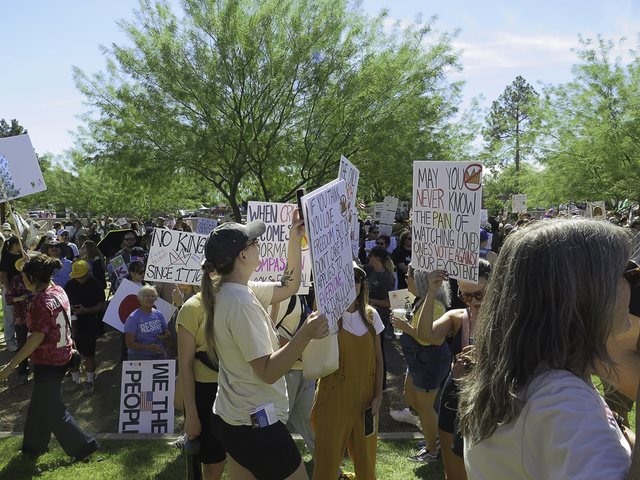 No Kings 2.0 protest signs in Phoenix reading May you never know the pain of watching loved ones vote against your existence and No King Since 1776