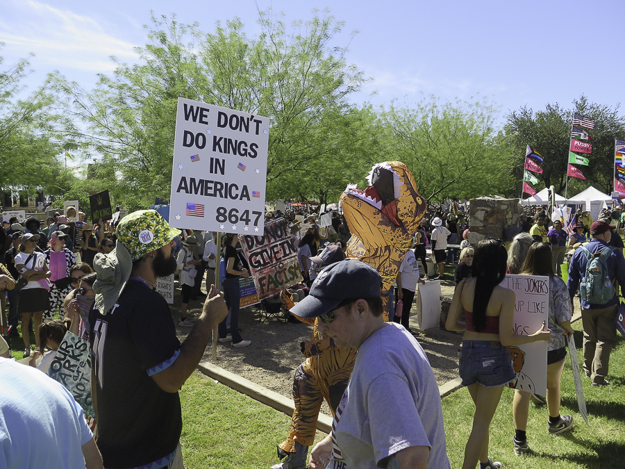 No Kings 2.0 demonstrators in Phoenix holding signs reading We Don't Do Kings In America 8647 and Do Not Give In To Fascism