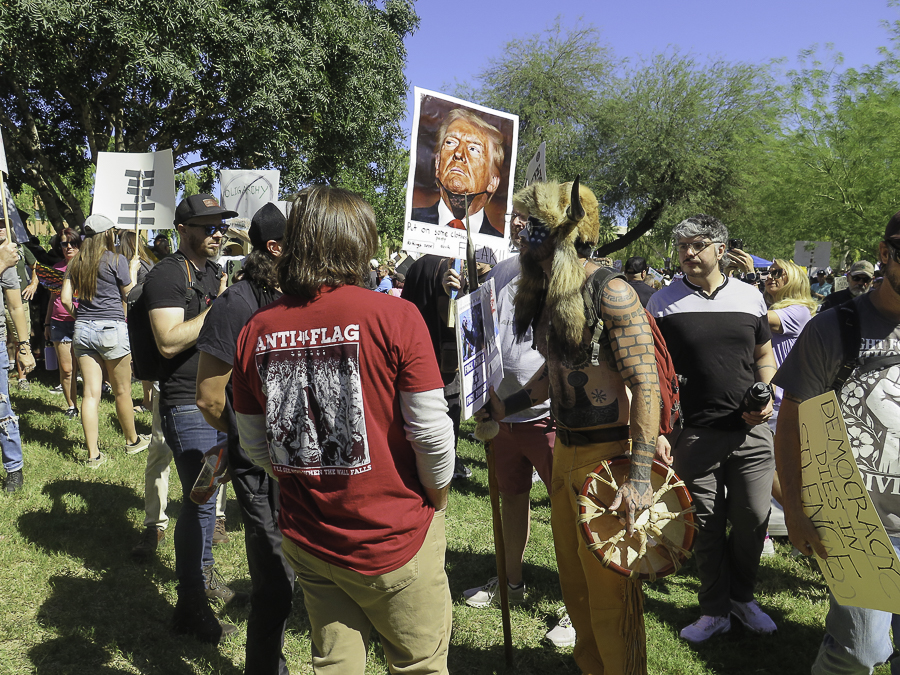 Jacob Chansley QAnon Shaman holding a drum at the No Kings 2.0 protest in Phoenix next to an Anti-Flag shirt