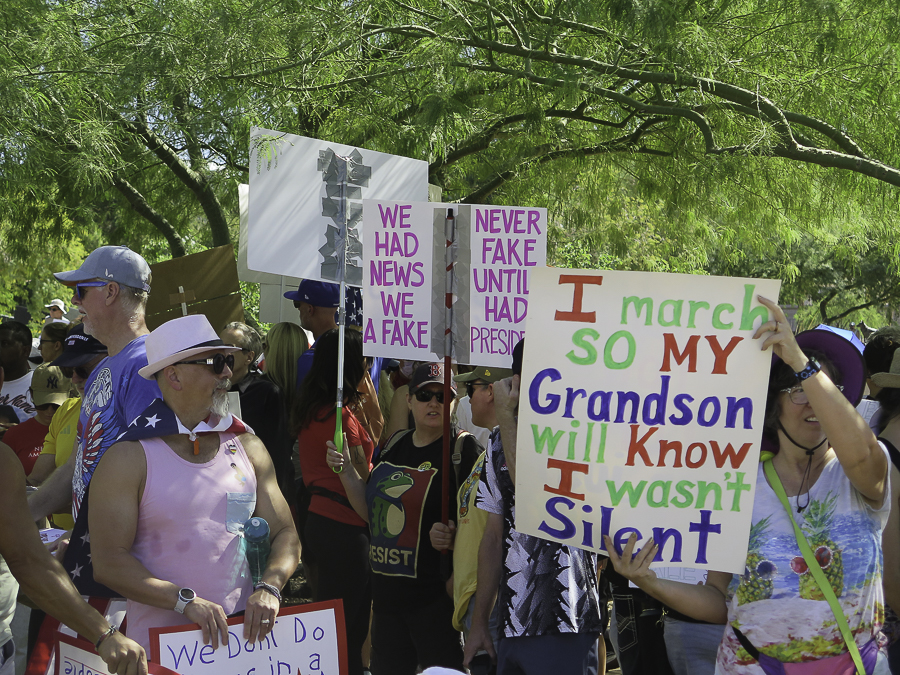 No Kings 2.0 demonstrators in Phoenix with signs reading I march so my Grandson will know I wasn't silent and We had news we have a fake