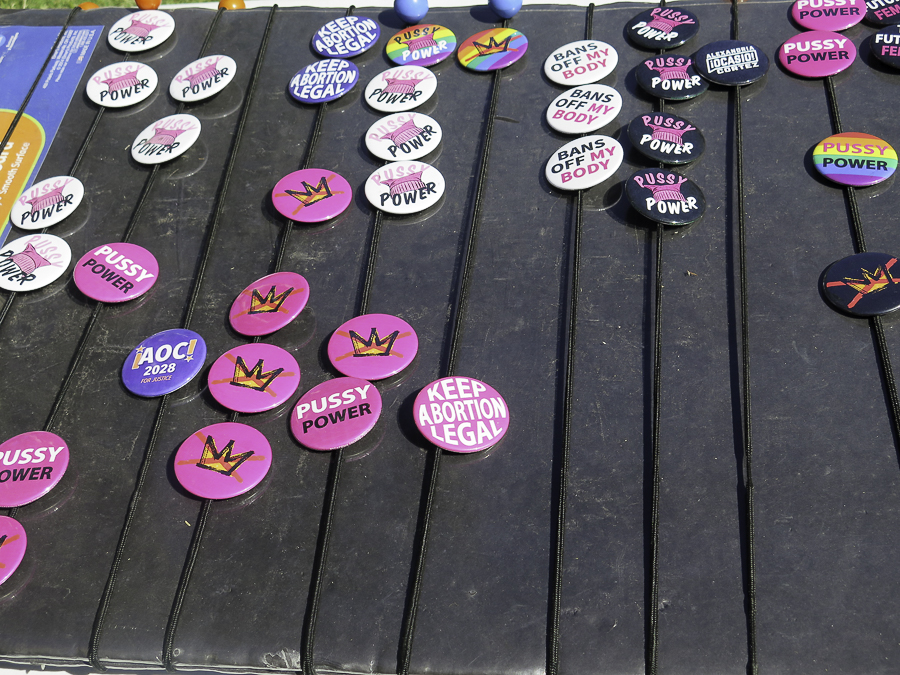 Activist merchandise pins at No Kings 2.0 Phoenix rally featuring AOC 2028 For Justice campaign button, Keep Abortion Legal, and No Kings logo