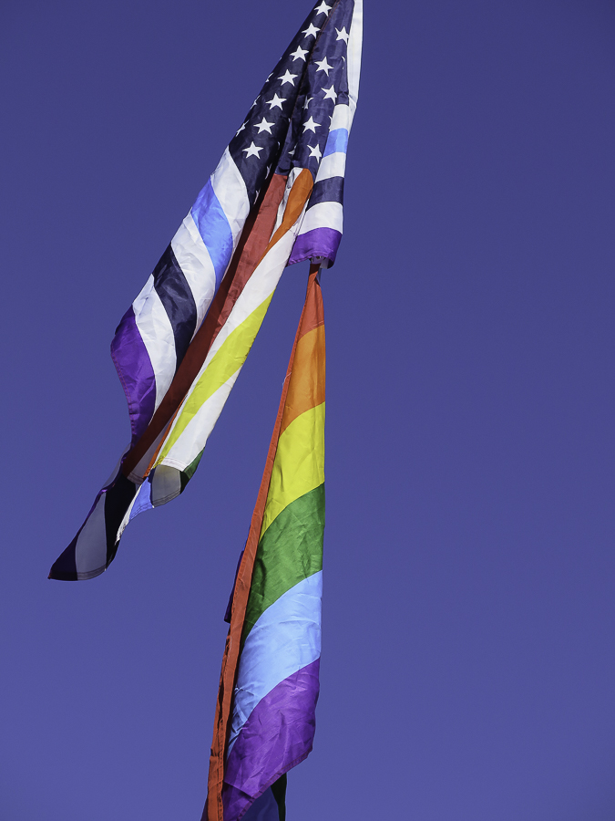 LGBTQ Pride rainbow flag and rainbow striped American flag waving at Phoenix No Kings 2.0 protest