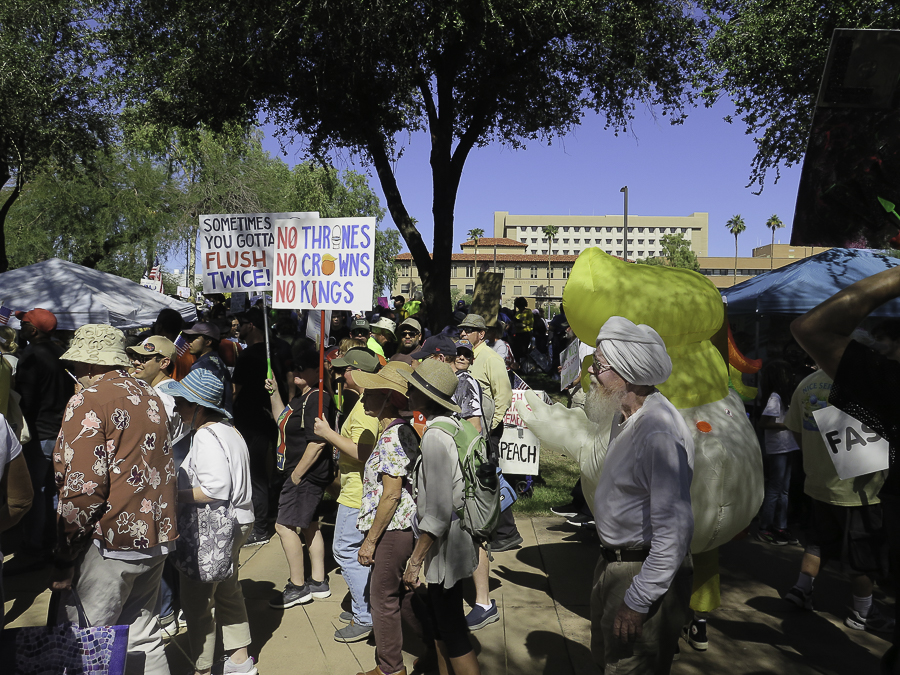 Activists and an inflatable yellow duck costume at Phoenix No Kings 2.0 rally with signs reading No Thrones No Crowns No Kings