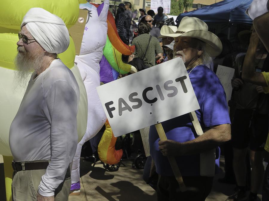 Phoenix No Kings 2.0 demonstrator in a cowboy hat holding a Fascist sign next to an inflatable unicorn costume