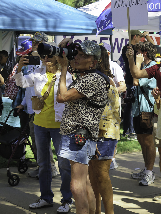 Press photojournalist using a Canon DSLR camera and telephoto zoom lens to document the Phoenix No Kings 2.0 rally