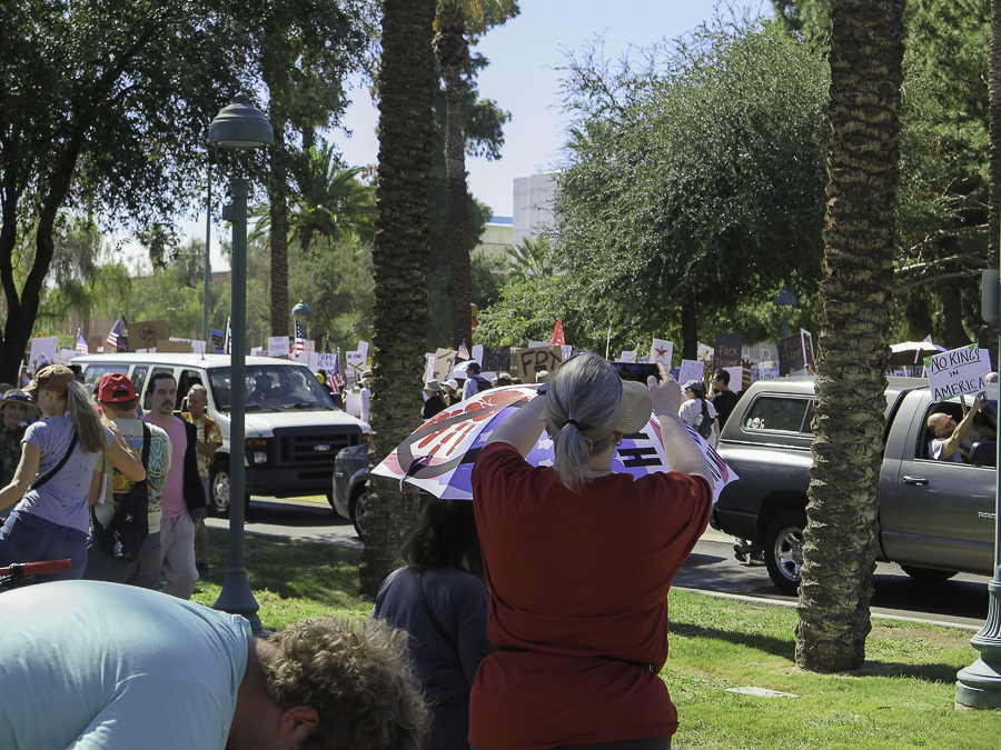 Demonstrators holding up a No Kings In America sign from a vehicle during the Phoenix protest street march